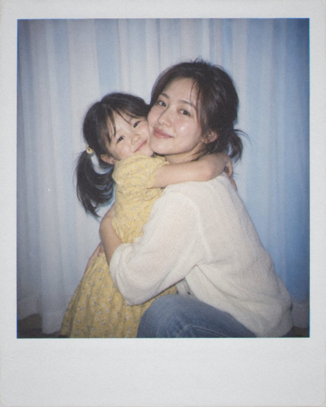 양 갈래 머리 어린 시절의 나를 무릎 꿇고 안아 주는 여성의 폴라로이드 사진