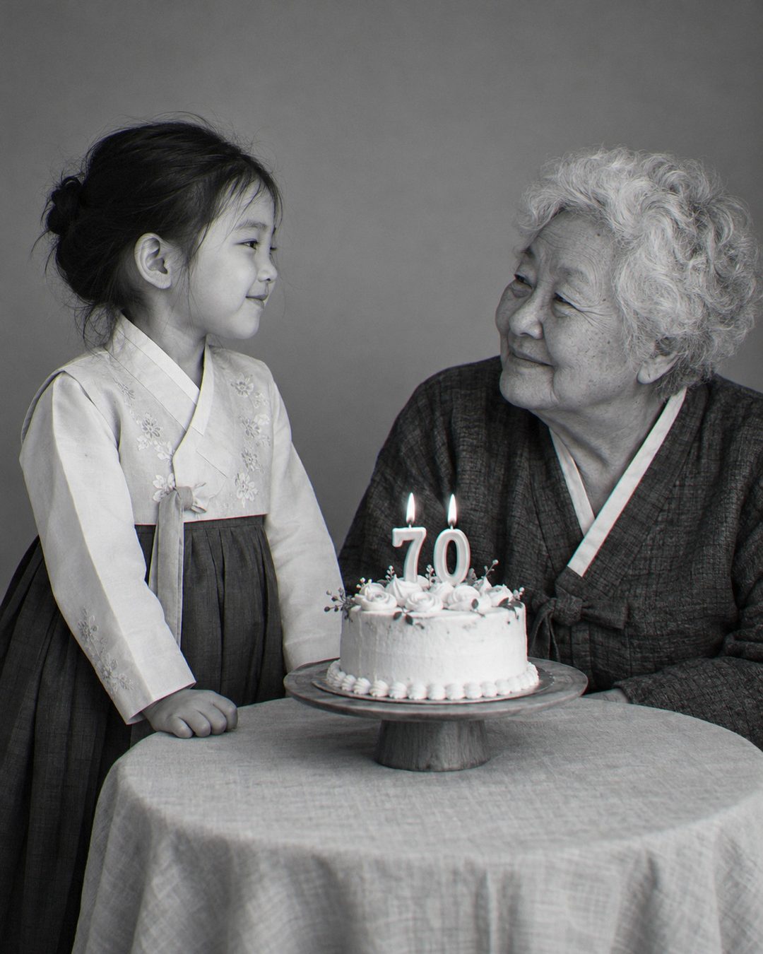 할머니가 된 나와 어린 시절의 나가 마주 보는 흑백 생일 케이크 사진